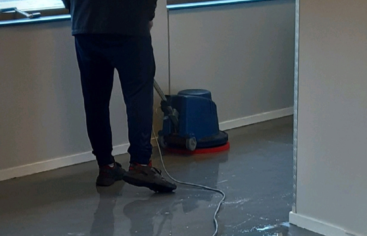 Medewerker bedient een schrobmachine op een bedrijfsvloer